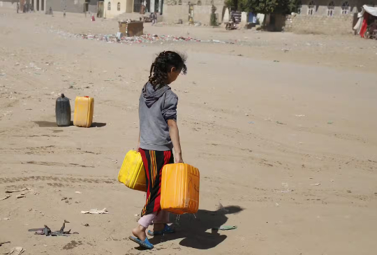 Jemenitiese meisie hou waterjerrikanne vas nadat hulle dit volgemaak het uit 'n geskenkte tenk te midde van 'n watertekort