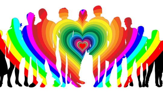 eine Gruppe von Menschen, die in einem regenbogenfarbenen Herzen stehen