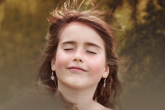Eine junge Frau lächelt mit geschlossenen Augen