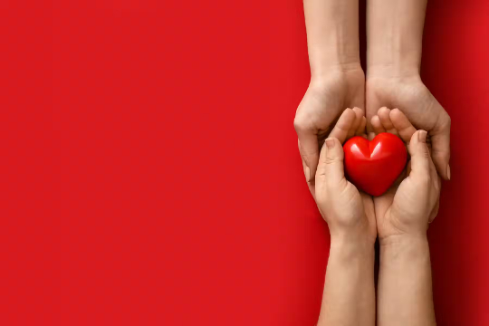 young hands holding a glowing red heart-shaped stone