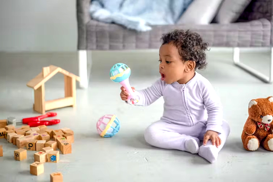 un bebeluș care stă pe podea jucându-se cu jucării