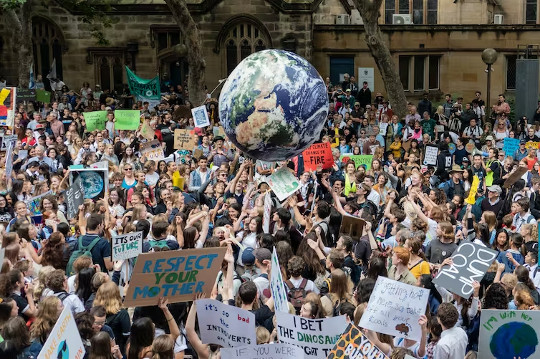 mga nagpoprotesta na may hawak na malaking globo ng Planet Earth