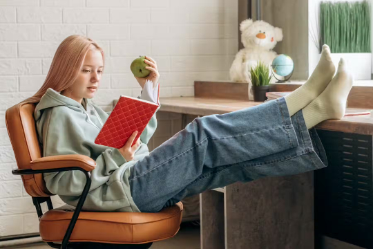 una niña estudiando y comiendo una manzana