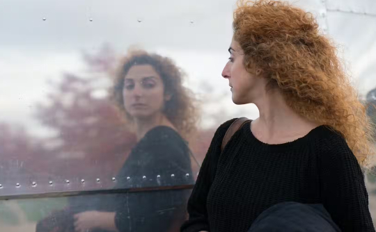 una mujer revisando su reflejo mientras camina