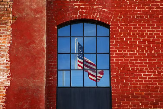 een Amerikaanse vlag gezien door een raam in een rode bakstenen muur