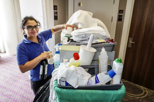 femme de ménage de l'hôtel avec un chariot plein de produits chimiques de nettoyage