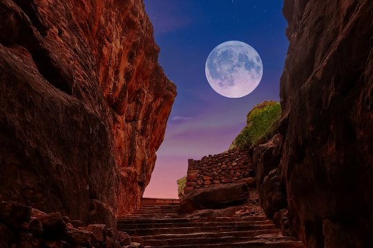 een volle maan omgeven door rode rotsen