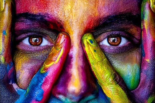 ένα πρόσωπο καλυμμένο με διάφορα φωτεινά και ζωηρά χρώματα