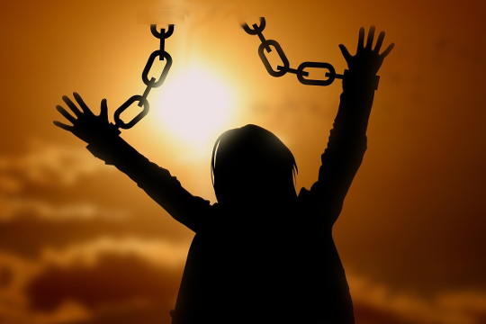 a person with hands up in the air with handcuff chain broken