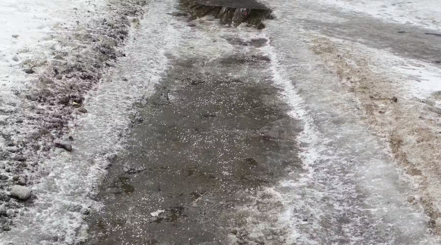 Ein verschneiter Bürgersteig, bedeckt mit winzigen Salzbrocken.
