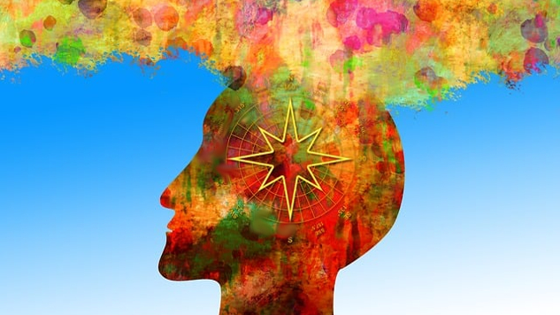 一個人的頭部的側視圖充滿了多種顏色，上面盤旋著彩色的雲