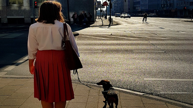 seorang wanita dengan seekor anjing di jalan yang sebagian besar kosong