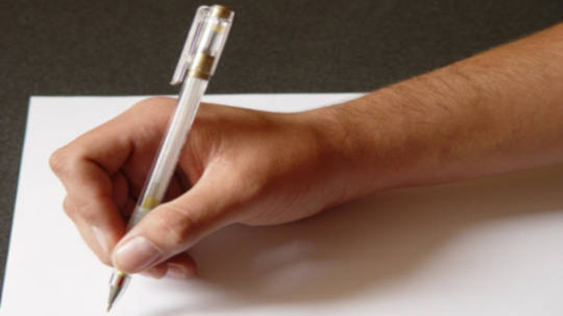en persons hånd holder en kuglepen og skriver