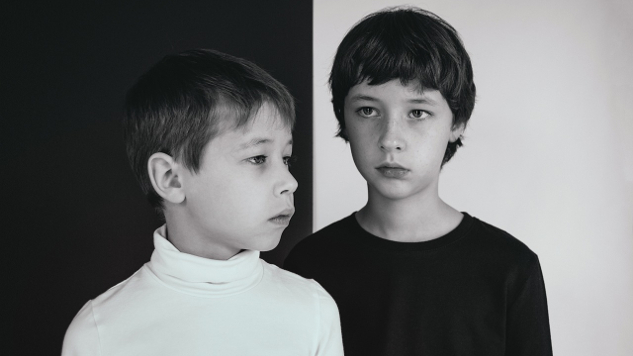 to unge gutter, den ene kledd i hvitt, den andre i svart foran en kontraherende bakgrunn