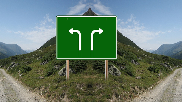 ein Schild an einer Straße mit Pfeilen, die in verschiedene Richtungen zeigen: nach links oder rechts