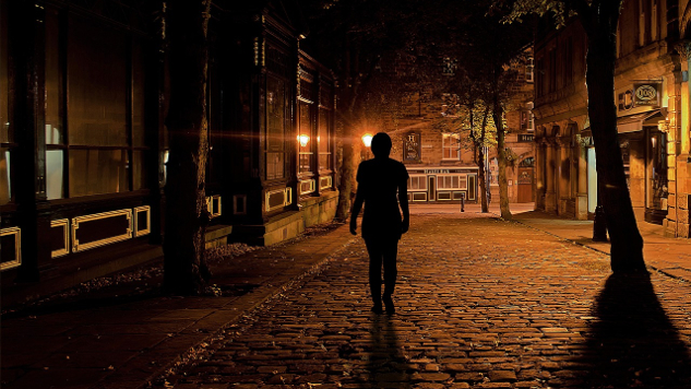 person som går ensam på en mörk gata