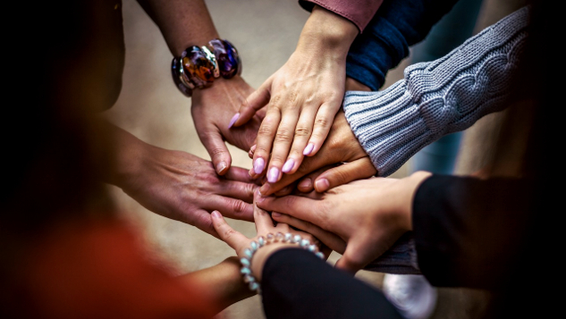 numerous hands in a circle, touching