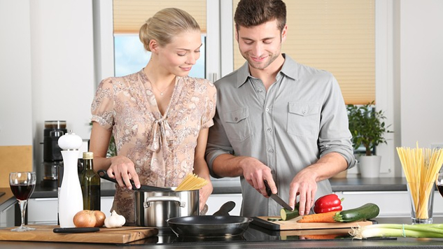 en mann og kvinne lager mat sammen på kjøkkenet