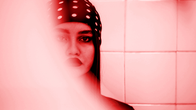 μια νεαρή γυναίκα στον καθρέφτη - το μισό της πρόσωπο κρυμμένο στον ατμό