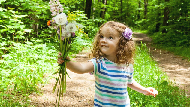 young girl holding out a bunch of wildflowers