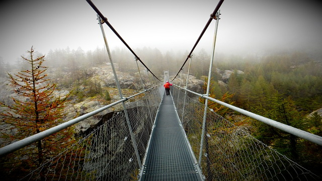 een touwbrug over een kloof met één persoon in het midden van de brug