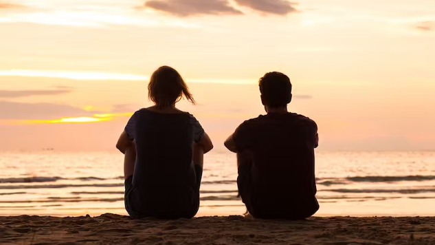 dua orang duduk di tepi lautan