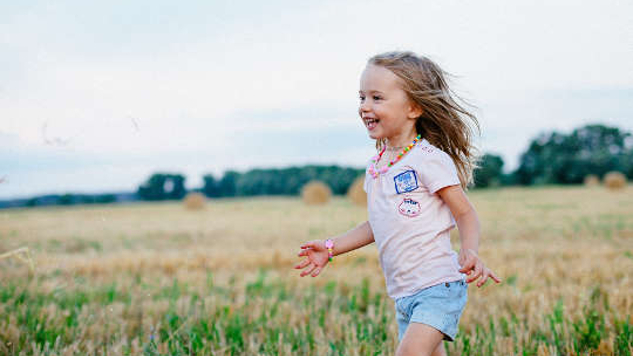 een vrolijk jong kind dat door een veld rent