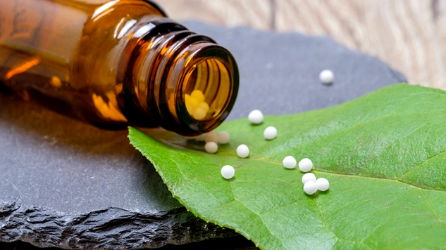 homeopatiske kuler helles ut på et blad