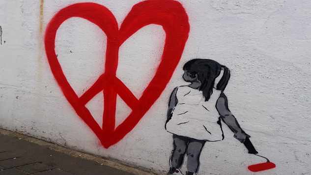 young girl painting a huge heart with a peace symbol inside
