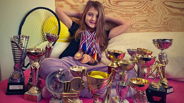 Una joven con muchos trofeos delante de ella.