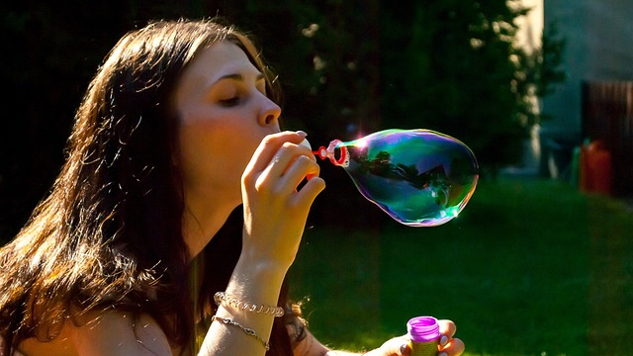 молодая женщина надувает мыльный пузырь