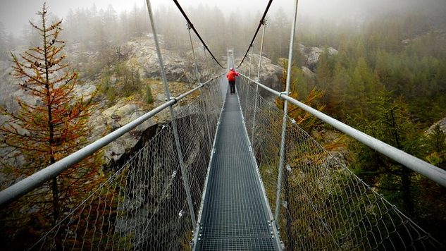person walking forward on a rope bridge