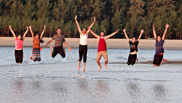 группа молодых людей посреди реки прыгает от радости