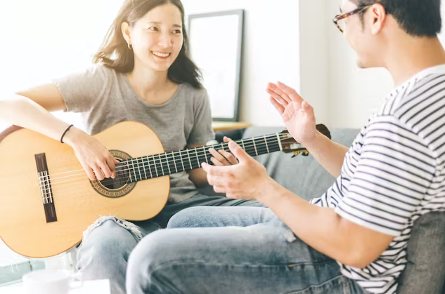 一个女人坐在她的伴侣面前弹吉他