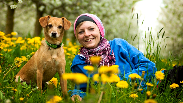 Mujer y perro tumbados en un campo de flores silvestres.
