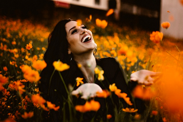 a woman laughing in a field of bright orange flowers
