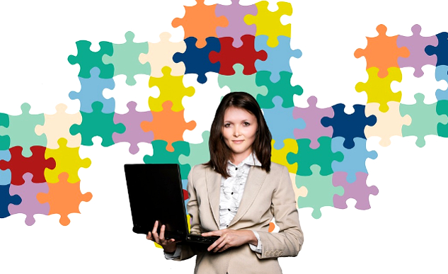 woman holding a laptop with a background of puzzle pieces on the wall behidn her