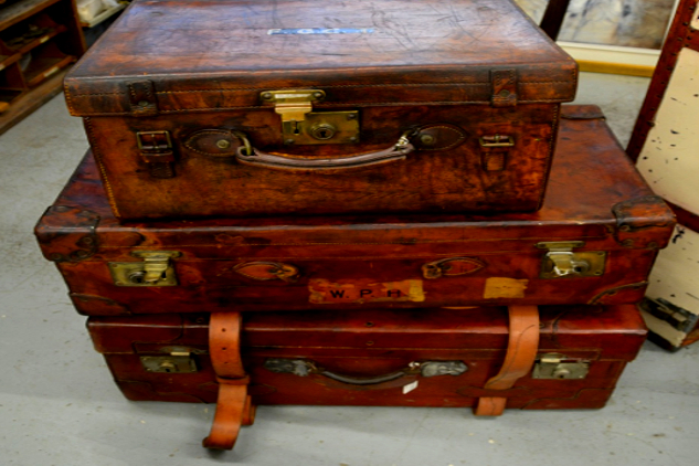 tiga koper tua yang tidak diikat bertumpuk satu sama lain