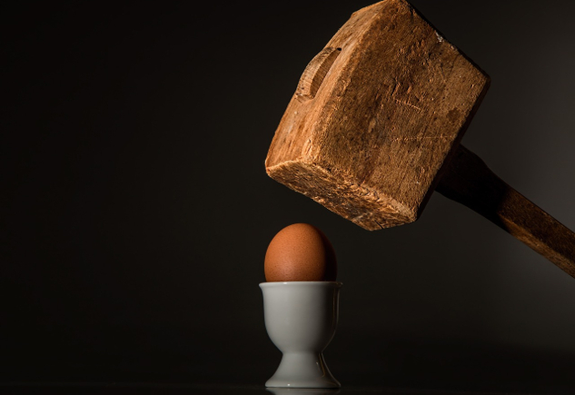 un martillo pesado sostenido sobre un huevo