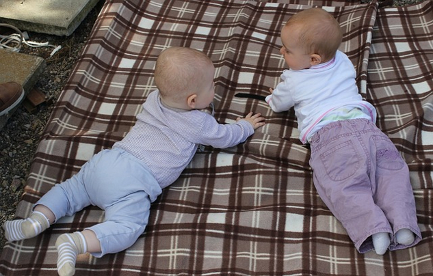 two babies communicating on a blanket