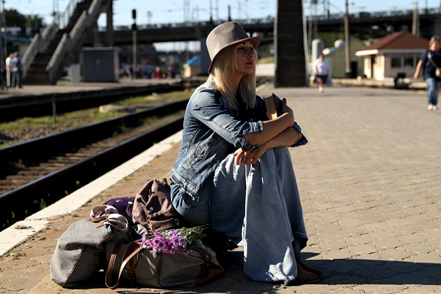 기차역에서 여행가방 위에 앉아 있는 여자