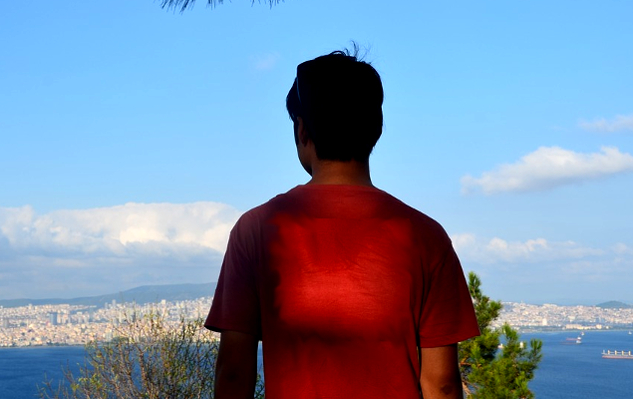 Un joven con un corazón que irradia luz está parado en una colina con vistas a una ciudad