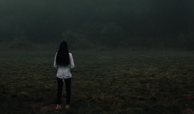 Frau steht allein vor einer Nebelbank