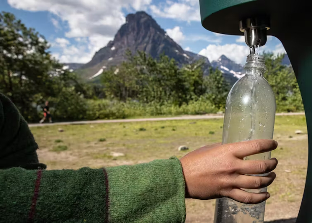 Eine Person, die eine Trinkwasserflasche an einem Außenzapfhahn nachfüllt