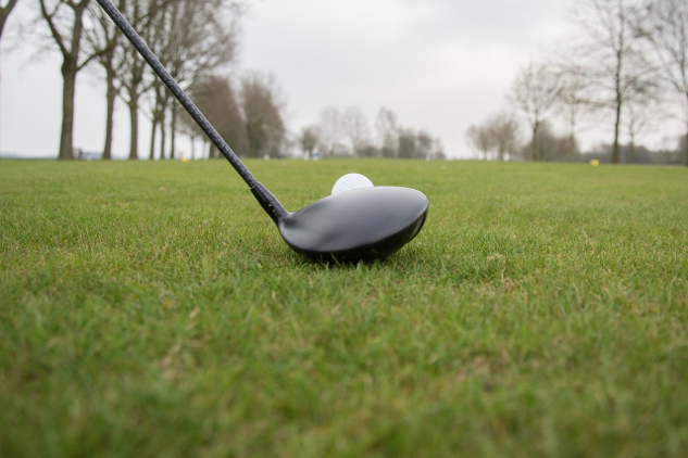 et nærbilde av en golfkølle satt rett foran en golfball