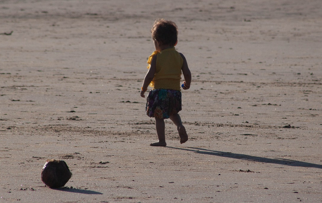 seorang kanak-kanak yang sangat muda bersendirian di pantai