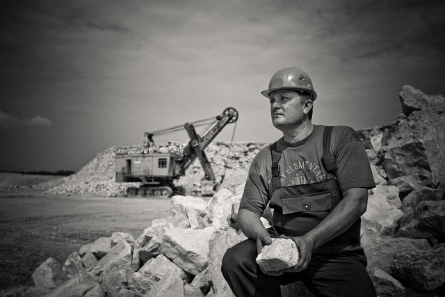 ผู้ชายกำลังนั่งถือหินก้อนใหญ่ในสถานที่ก่อสร้าง