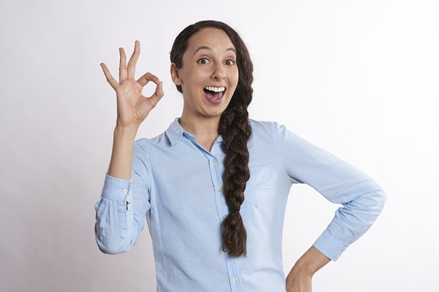 mujer con una gran sonrisa y dedos en un símbolo "a-ok"