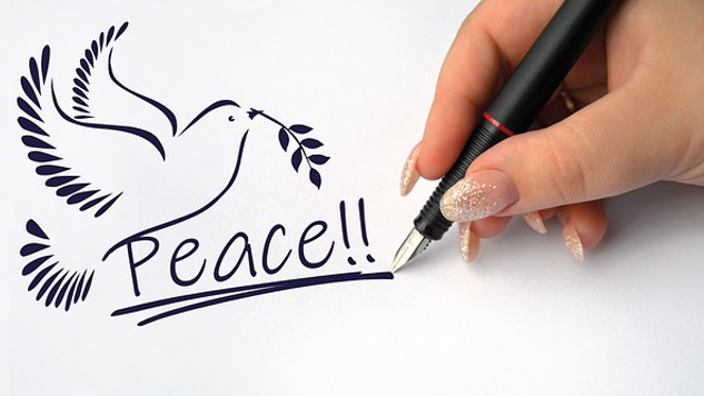 en hånd som skriver ordet fred og tegner en due som holder en olivengren
