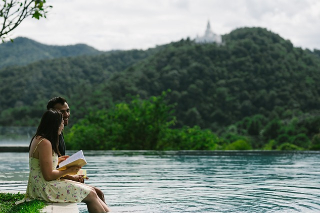 คู่รักนั่งอยู่ริมทะเลสาบอ่านหนังสือ